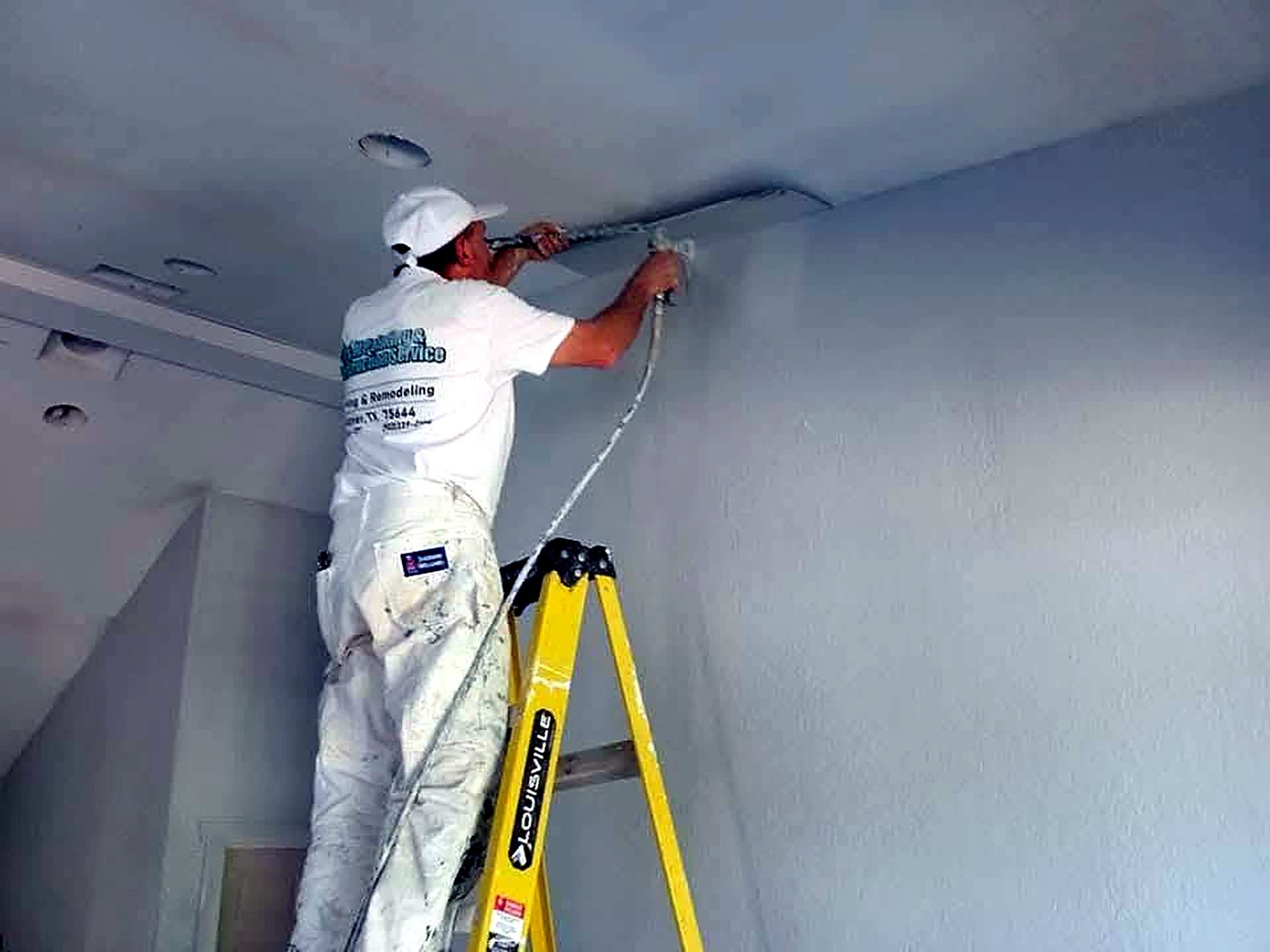 R&M painter finishing an interior ceiling with a spray rig